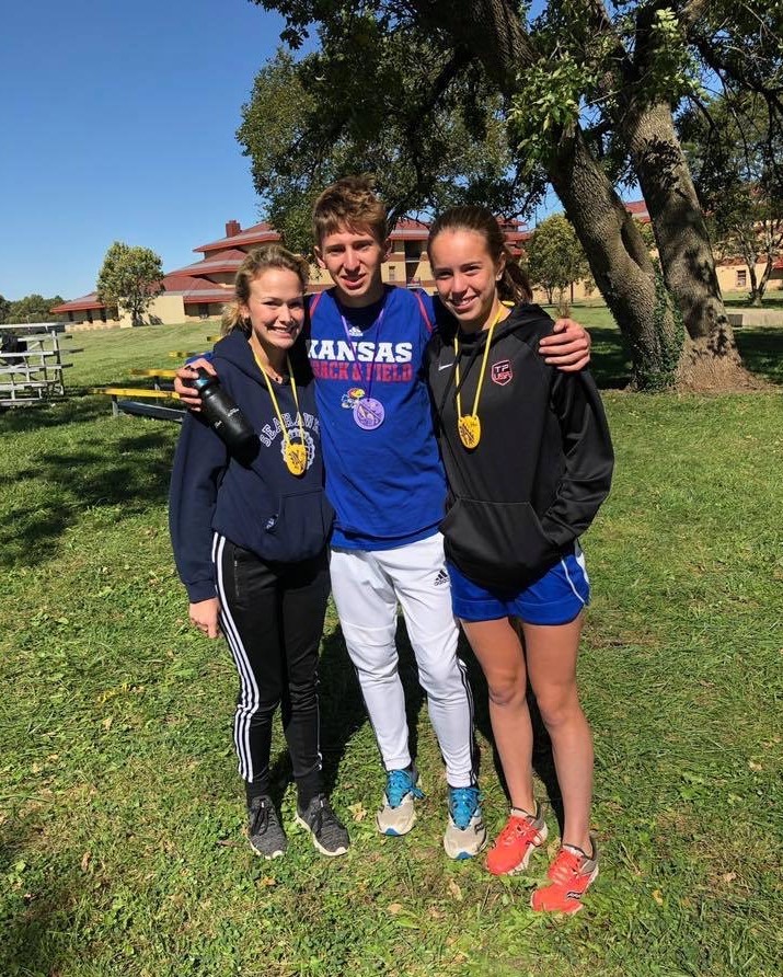 Seniors Sabrina Eicher, Henry Nelson and freshman Oona Nelson pose for a photo at Haskell. Haskell was a unique meet because it is the one meet that gave the runners hand-made metals