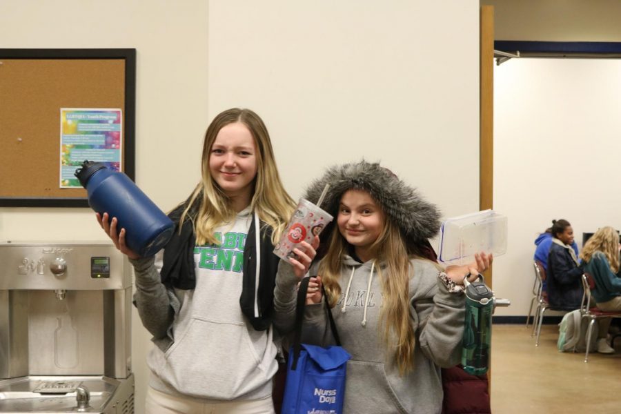 Eighth graders Alexandra Terry and Eve Tuckel pose with lost and found items. Student's missing items can usually be found in the bins in front of Ms. Czarnecki's room... unless someone else took them first 