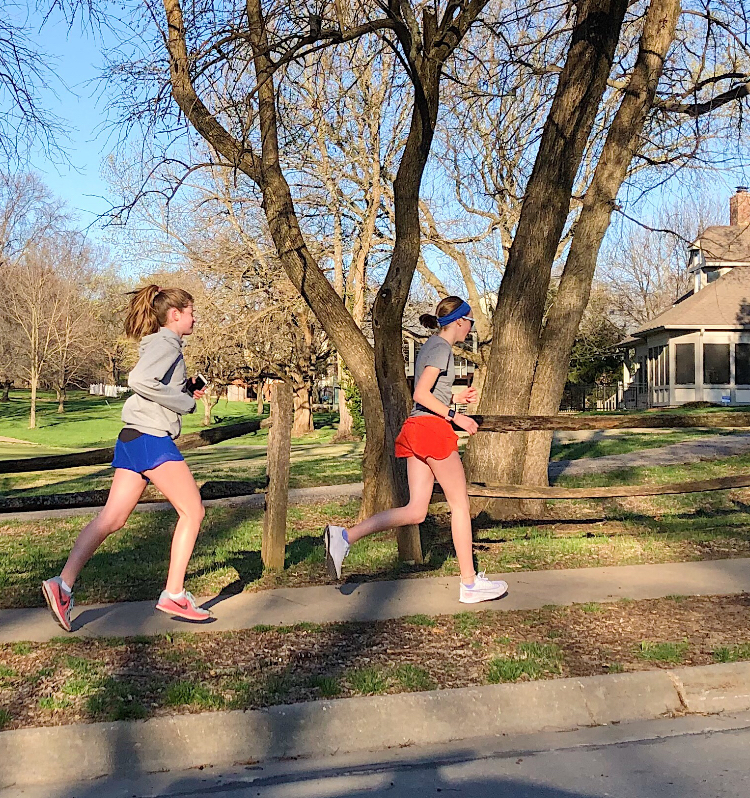 Eighth graders Campbell Helling and Isabelle Pro run through a neighborhood. Pro showed huge dedication to running by running a half marathon on her own when her race was canceled.