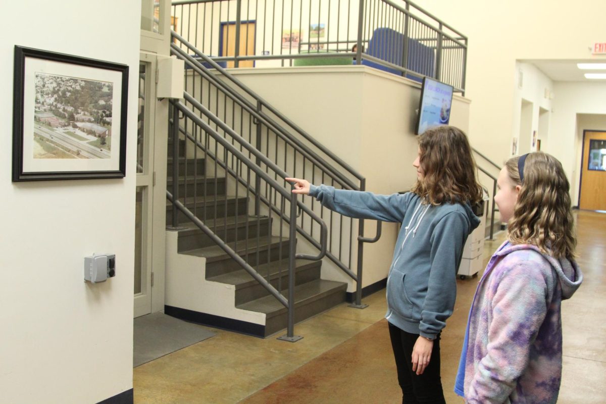 Sixth grader Lily Weiss points out a picture of Seabury’s original building to her shadowing student Aria. Weiss participated in a visit day of her own last year. 
