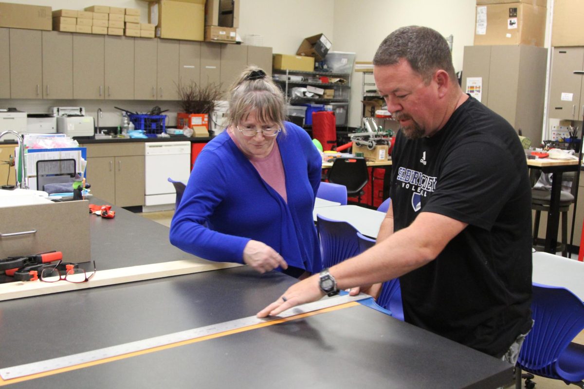 Faculty members Eric Neuteboom and Julie Pearce measure a desk. Neuteboom says he would love to take a Wood Working class.