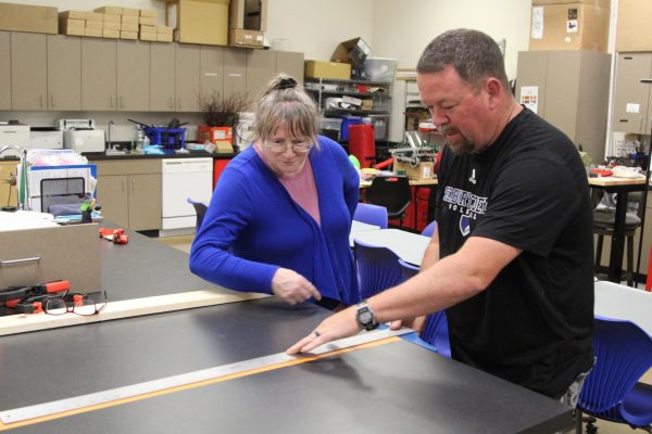 Faculty members Eric Neuteboom and Julie Pearce measure a desk. Neuteboom says he would love to take a Wood Working class.