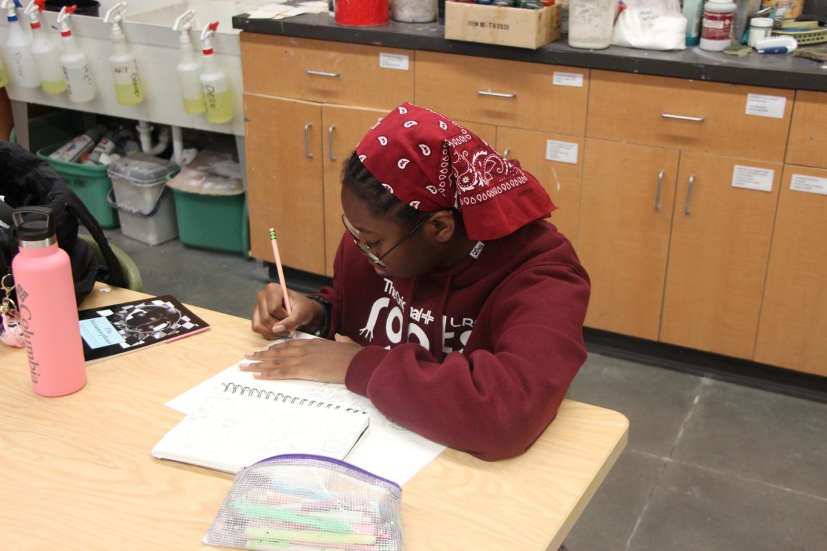 Sophomore Mina Tangara sketches a beautiful piece in Art. Currently, her self portrait hangs in the Commons where she is pictured sporting a fancy hat. 